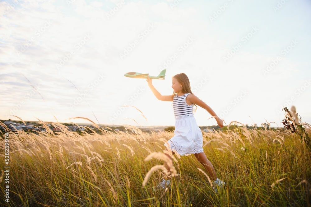 Happy girl runs with a toy airplane on a field in the sunset light. children play toy airplane. teenager dreams of flying and becoming a pilot. girl wants to become a pilot and astronaut. Slow motion. Happy girl runs with a toy airplane on a field in the sunset light. children play toy airplane. teenager dreams of flying and becoming a pilot. girl wants to become a pilot and astronaut. Slow motion.