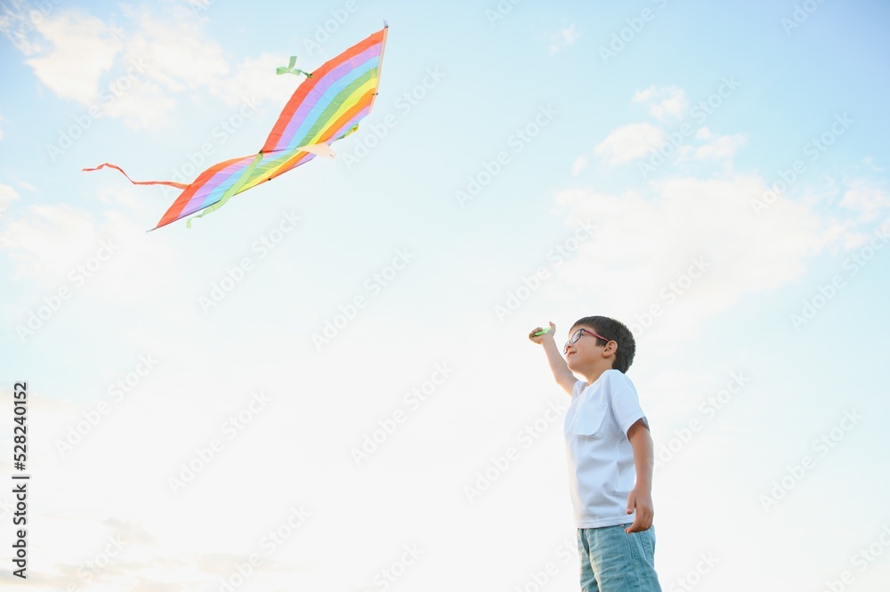 Boy is running with a kite during the day in the field