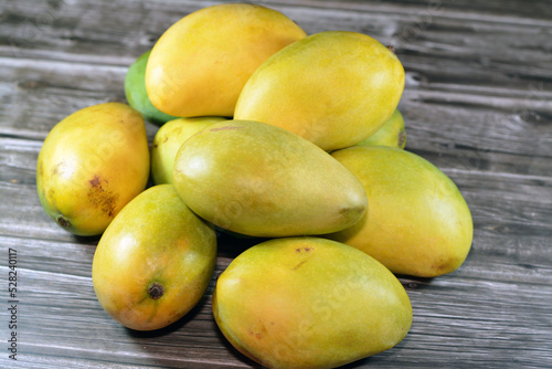 Pile of Egyptian fresh mango fruit with tropical delicacy, mangoes are nutritionally rich fruit with distinctive flavor, smell, taste, selective focus of Awaisy or Ewes Mango fruit isolated on wood photo