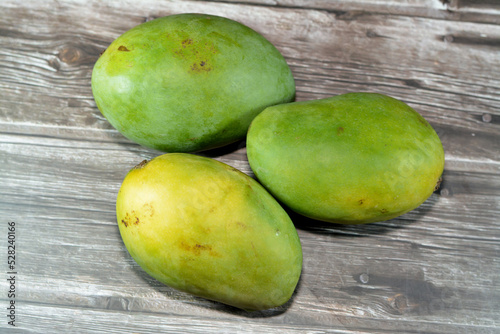 Pile of Egyptian fresh mango fruit with tropical delicacy, mangoes are nutritionally rich fruit with distinctive flavor, smell, taste, selective focus of Awaisy or Ewes Mango fruit isolated on wood photo