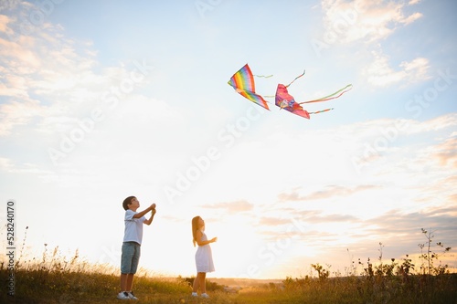 Children launch a kite in the field at sunset