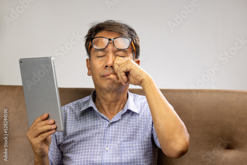 Senior asian man has eyestrain and fatigue photo