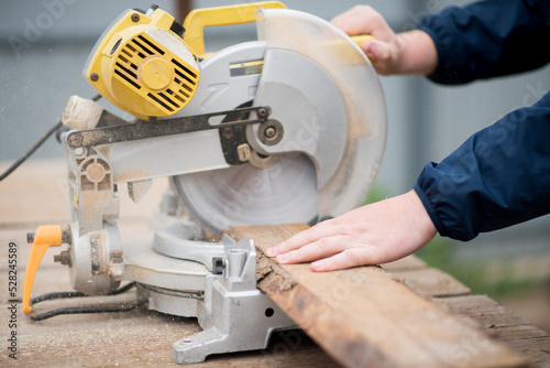 The man works with trimming saw. He is wearing a welder's protective mask and protective gloves. A rare working profession.