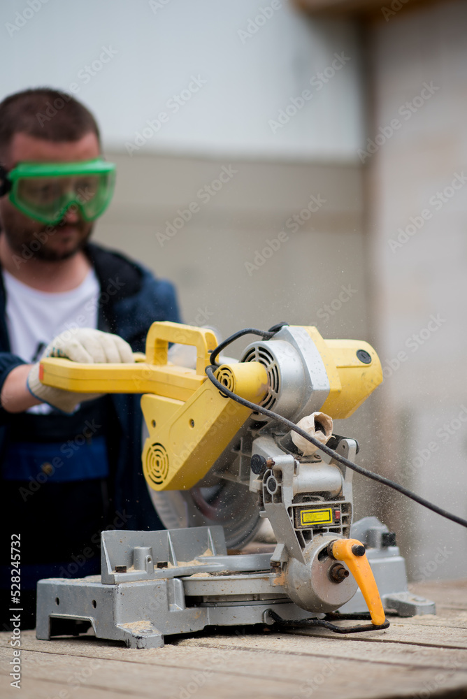 The man works with trimming saw. He is wearing a welder's protective mask and protective gloves. A rare working profession. The man works with trimming saw. He is wearing a welder's protective mask and protective gloves. A rare working profession.