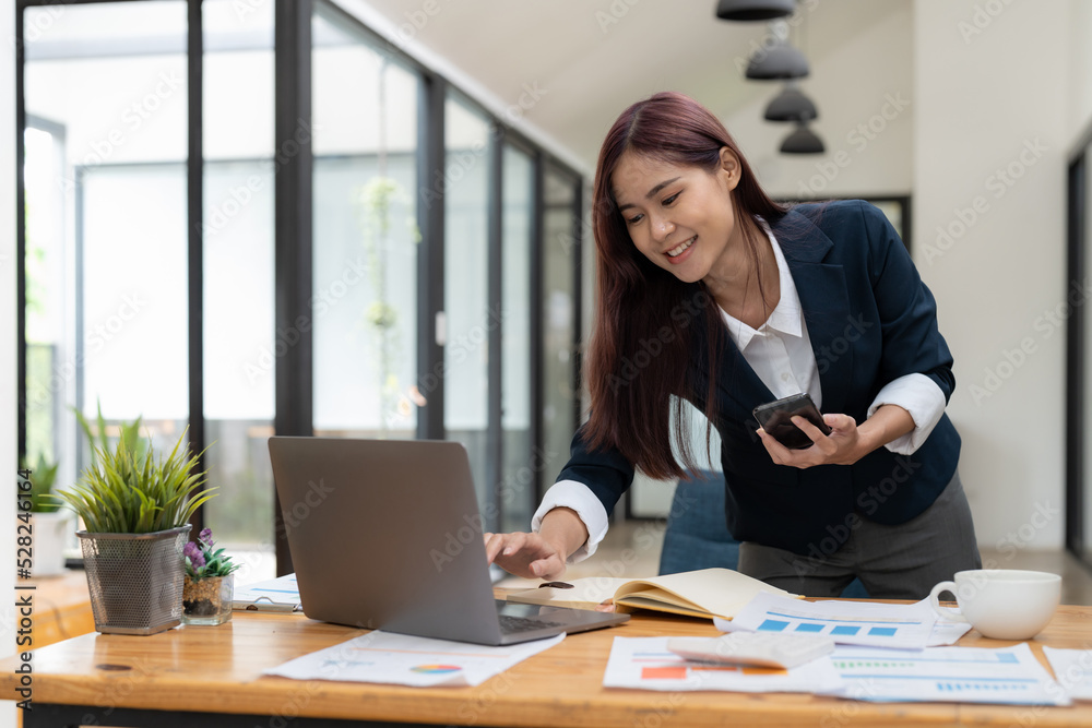 Business asian woman using mobile phone during checking an email or social media on internet. accounting financial concept. Business asian woman using mobile phone during checking an email or social media on internet. accounting financial concept.