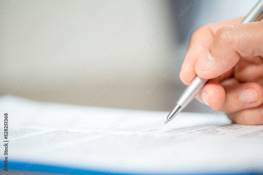 Workplace closeup person professional businesswoman sitting at desk hold pen signing or signature contract paper. Employee woman writing agreement document on paperwork form corporate at work office Workplace closeup person professional businesswoman sitting at desk hold pen signing or signature contract paper. Employee woman writing agreement document on paperwork form corporate at work office