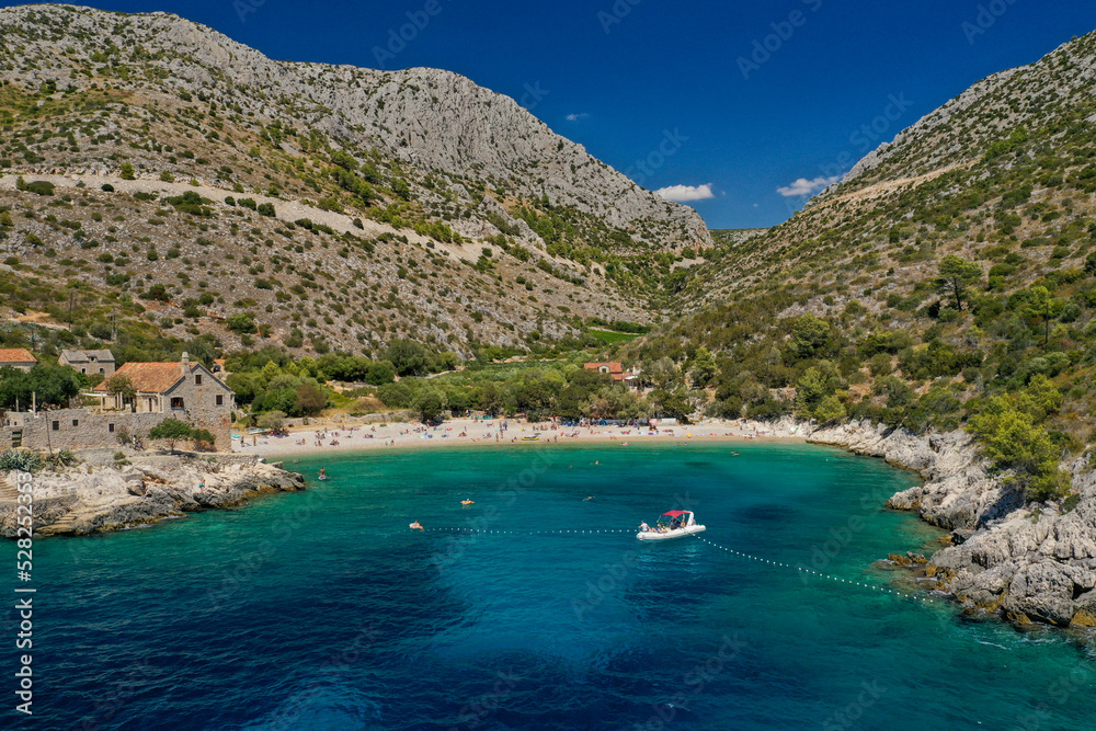 View on Dubovice Beach on the island of Hvar, Croatia with moored boats and many swimmers.