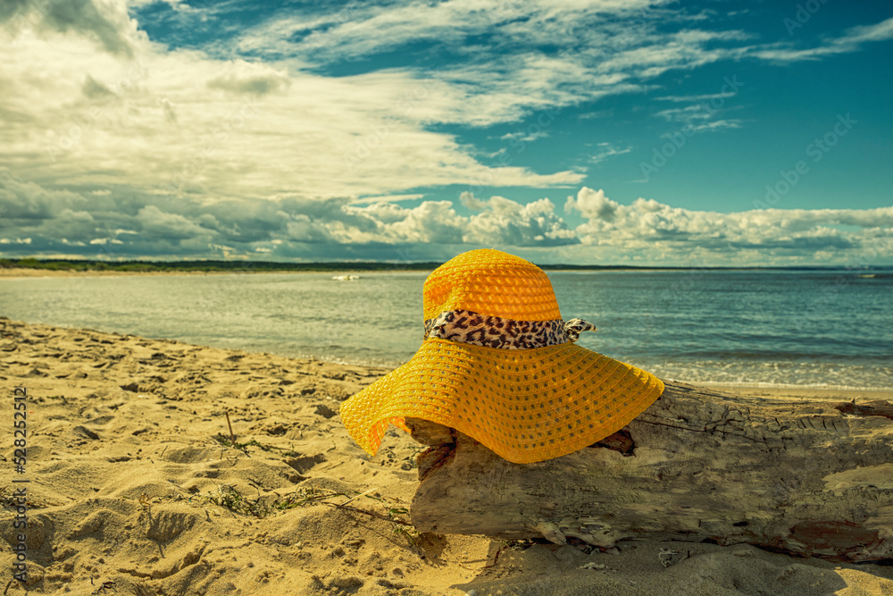 Żółty kapelusz na plaży, wakacje, piękny słoneczny dzień na plaży, morze, piasek.  - obrazy, fototapety, plakaty 