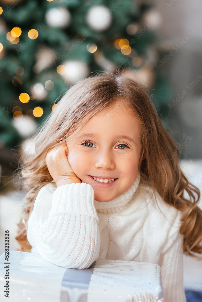 Close-up portrait of a little girl with big eyes and a wide sincere cute smile during the New Year holidays, the concept of Christmas