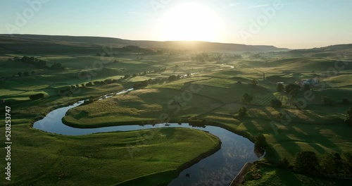 Flying over a calm river in the green valley