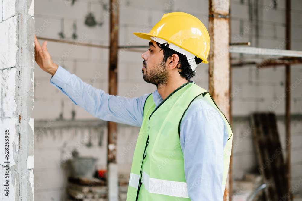 Construction worker with safety hardhat and in vest checking and analyzing an unfinished construction Construction worker with safety hardhat and in vest checking and analyzing an unfinished construction