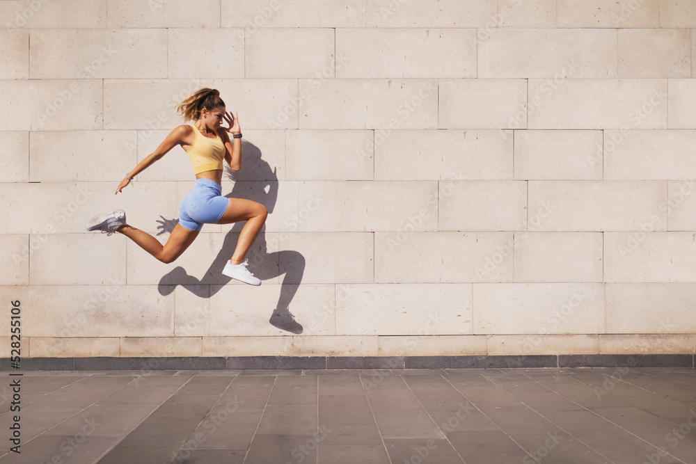 Jumped woman with a shadow on a wall background.