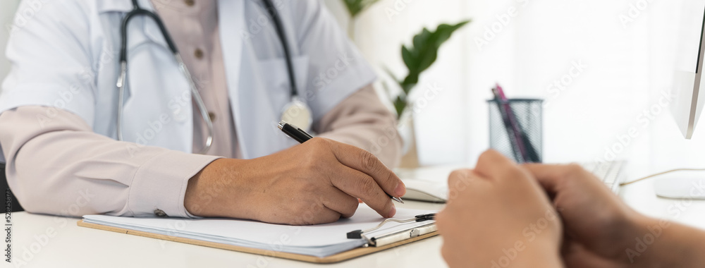 Close up doctor talking with the patient at a desk in the clinic Close up doctor talking with the patient at a desk in the clinic