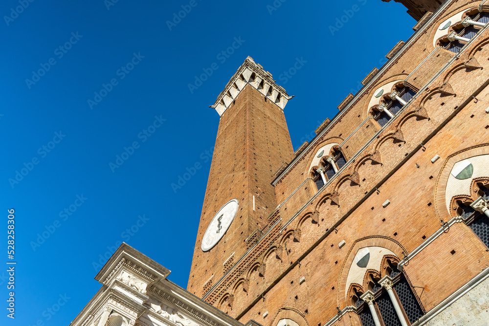 Obraz premium Low Angle View of Torre del Mangia and Palazzo Pubblico in Siena, Italy
