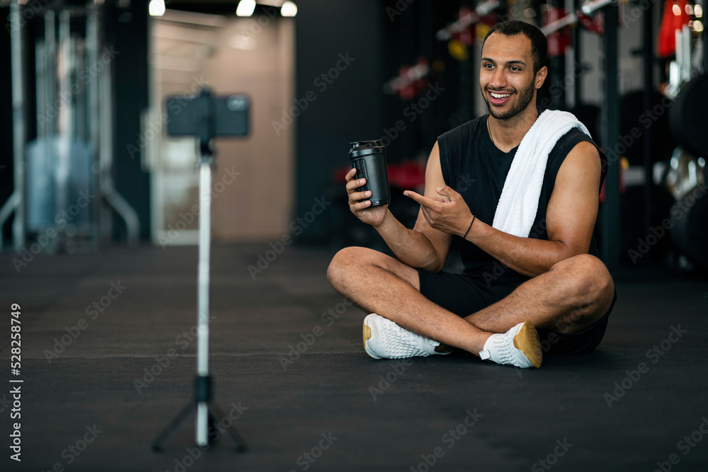 Naklejka premium Handsome Black Male Fitness Blogger Recording Video Review For Sport Shaker Bottle