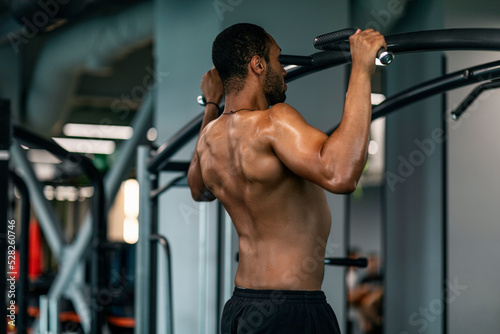 Athletic Young African American Man Pulling Up On Horizontal Bar At Gym