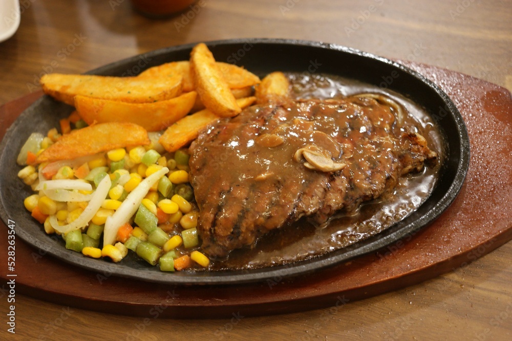 Steak served on the hot plate with potatoes and vegetables Steak served on the hot plate with potatoes and vegetables