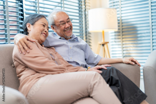 Senior couple sitting on the sofa at home watching television and relaxation together. Enjoyment to spend time together with smile and happy. Modern elderly lifestyle and retirement concept