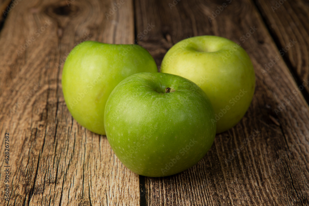 Green apple on a wooden background. An icon for a store for selling apples. Green apple on a wooden background. An icon for a store for selling apples.