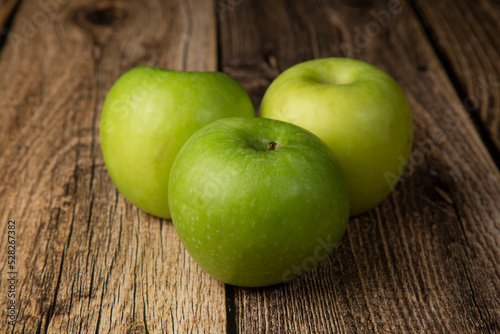 Green apple on a wooden background. An icon for a store for selling apples.
