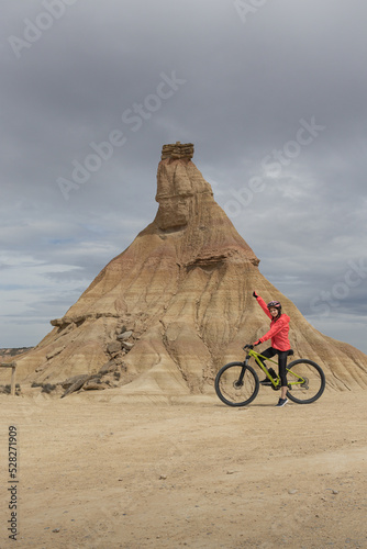 Young woman mountain bike cyclist next to Castildetierra Mountain in Badlans of Navarre (Bardenas Reales de Navarra) dessert in the middle of Spain.