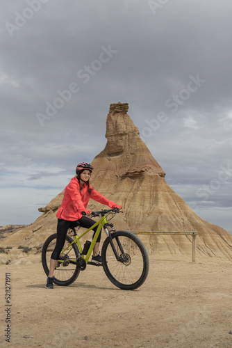 Fototapeta Young woman mountain bike cyclist next to Castildetierra Mountain in Badlans of Navarre (Bardenas Reales de Navarra) dessert in the middle of Spain