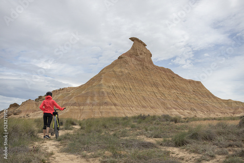 Fototapeta Young woman mountain bike cyclist in Badlans of Navarre (Bardenas Reales de Navarra) dessert in the middle of Spain