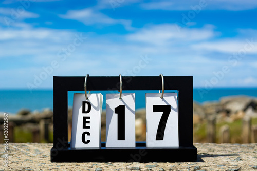 Dec 17 calendar date text on wooden frame with blurred background of ocean.