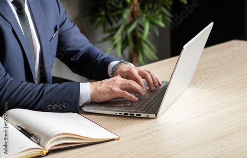 young businessman in a dark blue suit working in the office, typing on computer