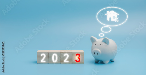 2023 on a wooden block cube with the white piggybank on blue background with copy space. The white piggy bank thinking of 2023 set goals for investment of property.