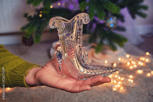 A woman holds a vase in the form of a crystal slipper in the palm of her hand at the Christmas tree