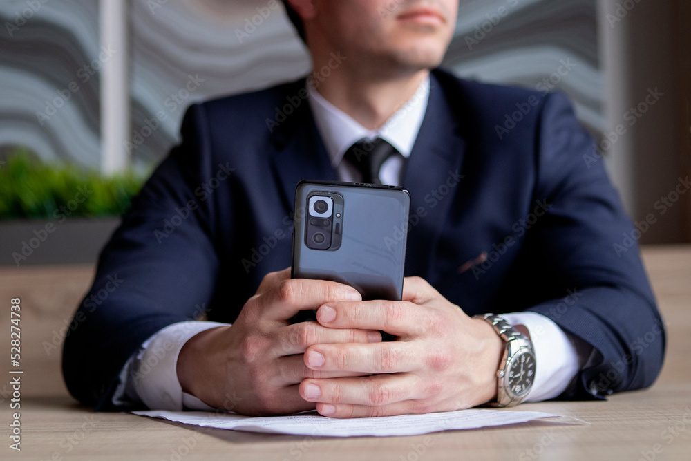 young businessman in a dark blue suit working in the office, typing on a mobile phone young businessman in a dark blue suit working in the office, typing on a mobile phone