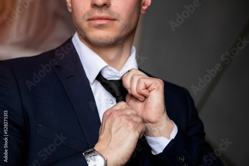 young businessman in a dark blue suit working in the office, tying a tie