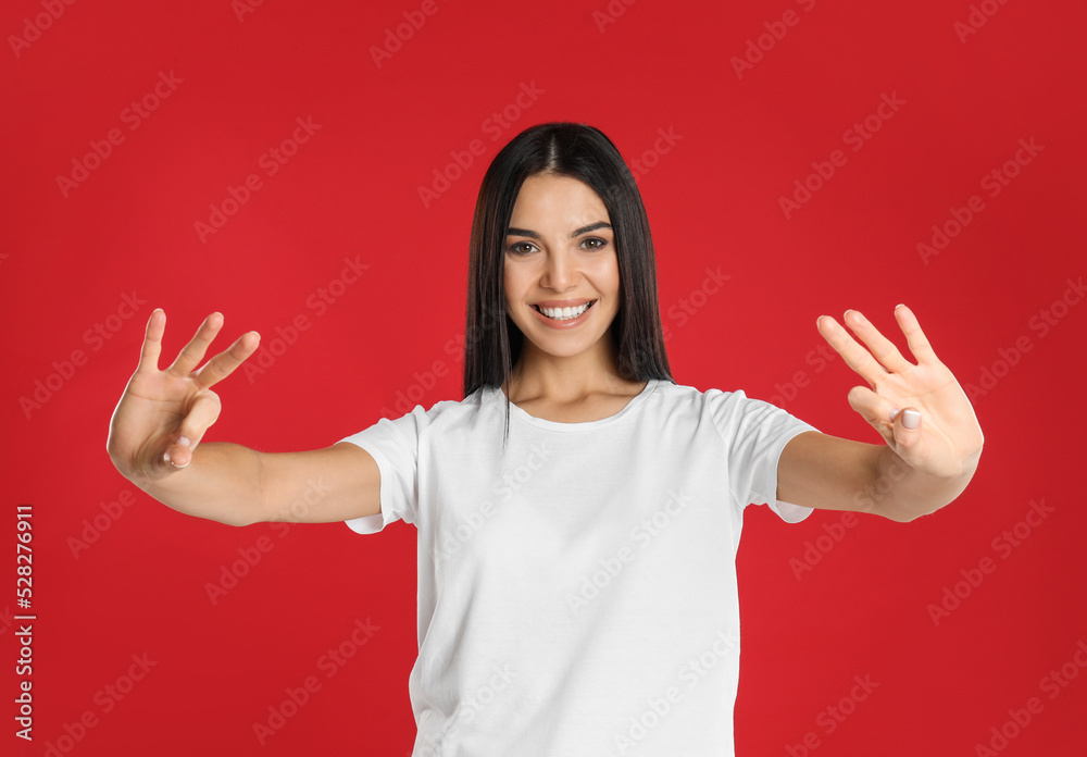 Woman showing number six with her hands on red background Woman showing number six with her hands on red background