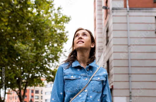 40-year-old adult woman looking up at the cloudy sky hoping for rain. drought in the city