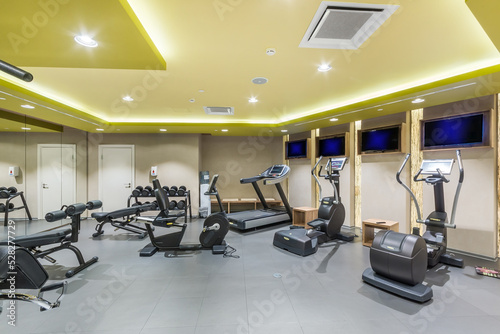 The interior of a modern gym with treadmills, exercise bikes and dumbbells for power loads.