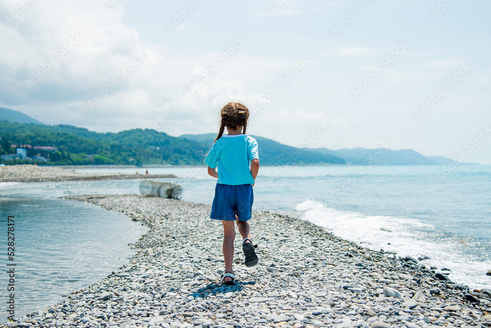 A little girl runs along the beach. Summer.