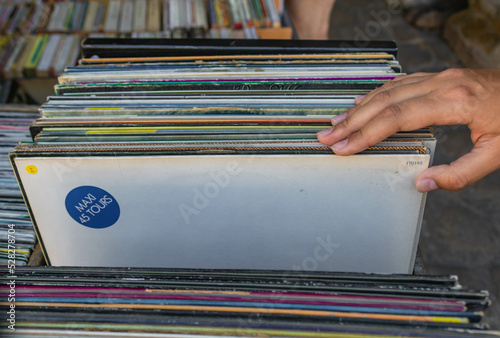 A woman's hand turns and looks at old longplay records in an antique store photo
