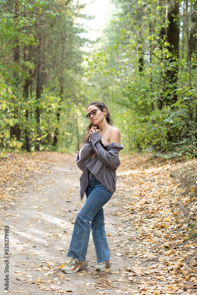Portrait of romantic woman at fairy forest. A beautiful young girl with glasses is walking through the forest. Girl purple suit. Corduroy fabric