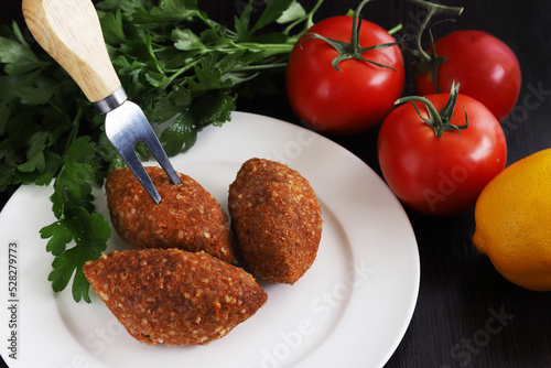 Ishli kufta. Beef kufta from lentils and bulgur. "Ishli kufta" with vegetables on the sides. Shallow depth of field