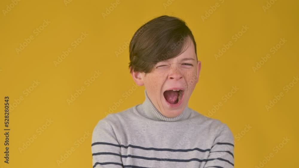 Bored sleepy young kid is yawning standing isolated on yellow studio background. Tired overworked teenager young boy yawning Bored sleepy young kid is yawning standing isolated on yellow studio background. Tired overworked teenager young boy yawning