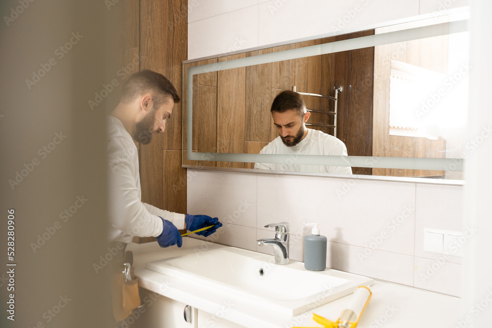 a worker installs a wash basin in a bathroom. a worker installs a wash basin in a bathroom.