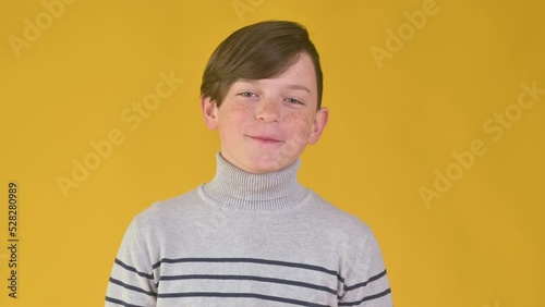 Happy little boy smiling and posing isolated on yellow background.