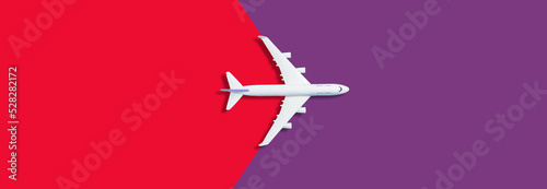 Flat lay of miniature toy airplane on red and purple background