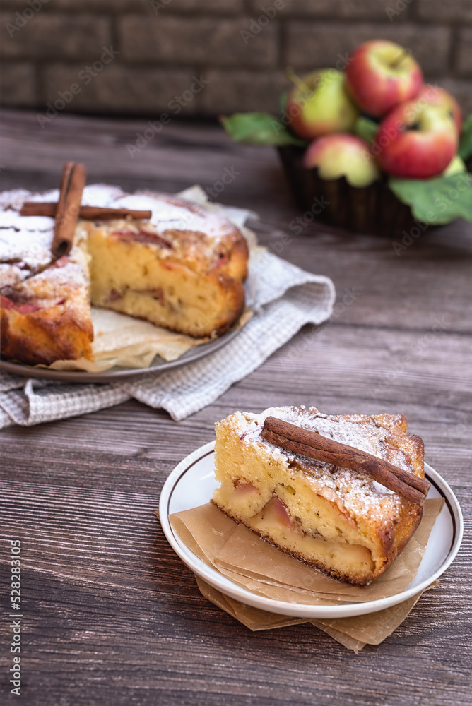 Homemade pie with apples and cinnamon on a dark wooden background. Homemade autumn pastries: a piece of apple pie and ripe apples on a wooden table. Homemade pie with apples and cinnamon on a dark wooden background. Homemade autumn pastries: a piece of apple pie and ripe apples on a wooden table.
