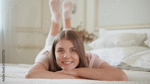 coquettish woman lying on the bed looking camera smiling happy morning at home photo