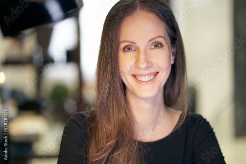 Portrait of happy smiling brunette caucasian woman looking at camera. Cheerful girl working at home.