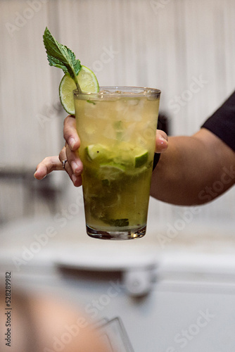 Bartender showing the customer the drink he has just prepared. Night club or party atmosphere. Classy drinks.