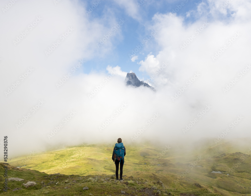 Girl with backpack hiking, Midi d?Ossau peak in the background in the Pyrenees National Park, France. Girl with backpack hiking, Midi d?Ossau peak in the background in the Pyrenees National Park, France.