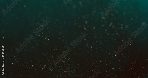 Particles background. Bokeh sparks texture. Blur glitter. Defocused teal blue golden shiny sparkles on dark color gradient abstract wallpaper.